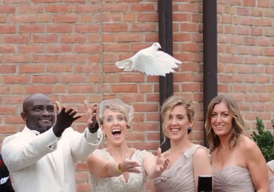 Wedding guests celebrating beside a brick wall
