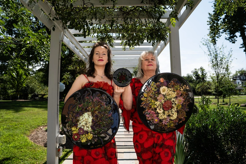 Alla and Milana Borovskaia holding floral artworks outdoors