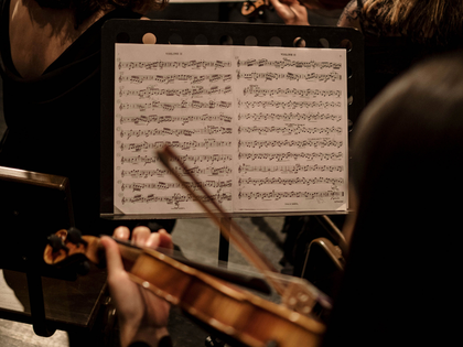 Violin players performing with sheet music on a music stand.