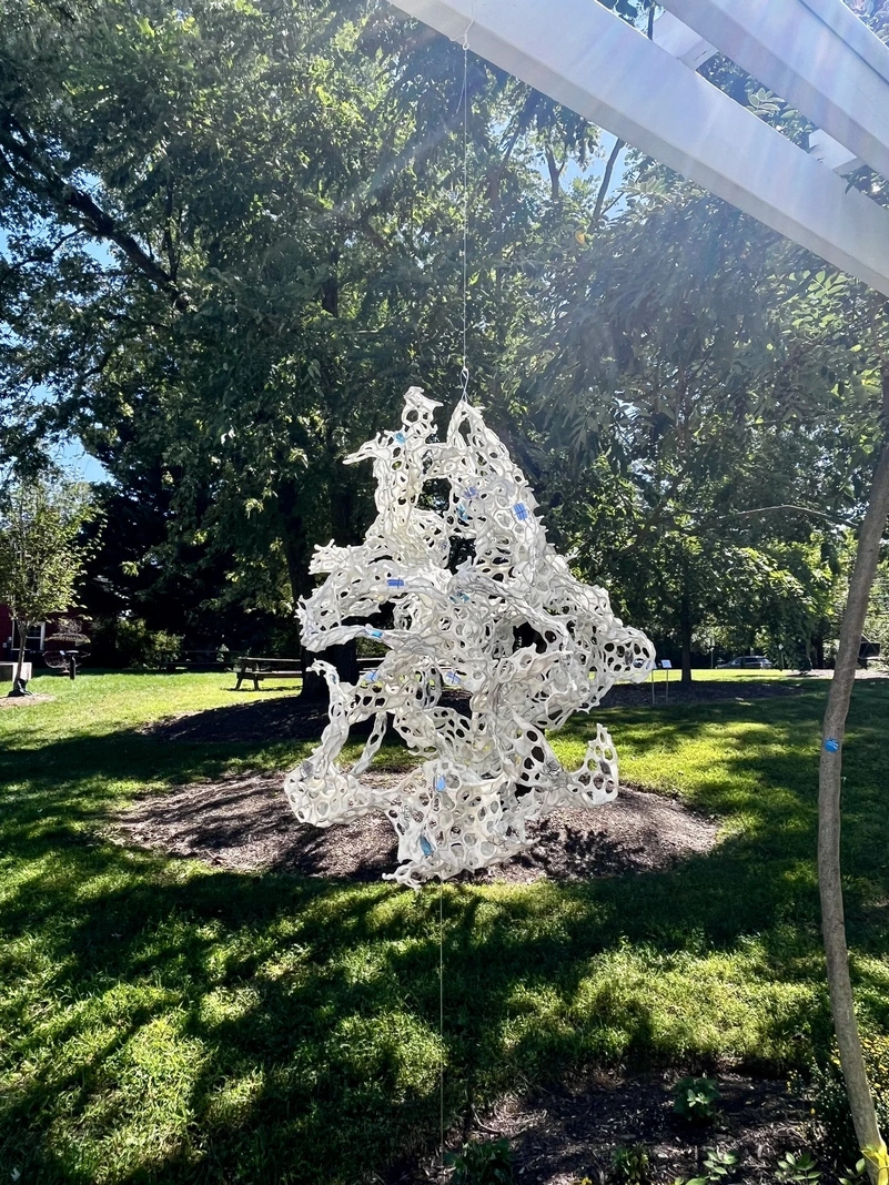 White openwork sculpture suspended outdoors at Sandy Spring Museum.
