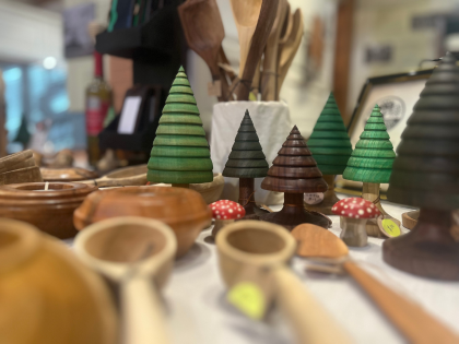 Handmade wooden bowls, utensils, and decorative trees on a display table.