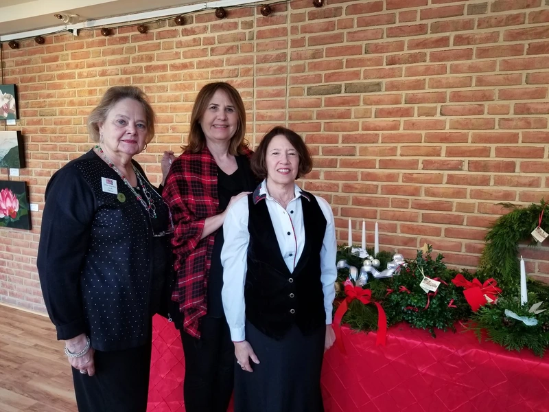Garden Club members standing beside a holiday greenery display